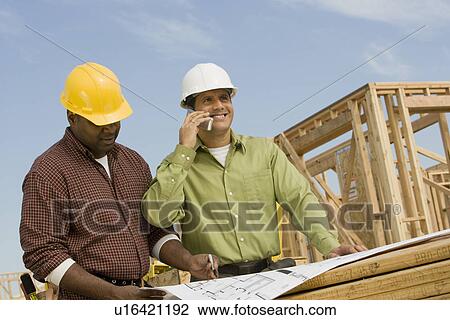 Stock Image - Surveyors working on construction site. Fotosearch