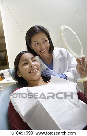 Stock Photo - Teenage girl (13-16) with dentist in surgery. Fotosearch