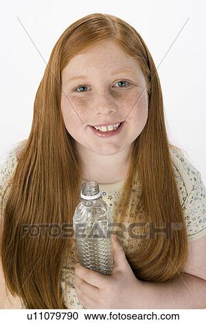 Stock Image - Teenage girl holding bottle, portrait. Fotosearch
