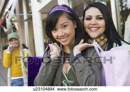 Teenage girls (16-17) with shopping bags in street, (portrait) View Large Photo Image Picture - Teenage girls (16-17) with shopping bags in street, (portrait). Fotosearch