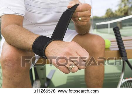Stock Photo - Tennis player putting on wristband. Fotosearch