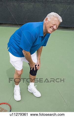 Stock Image - Tennis player suffering from knee injury. Fotosearch