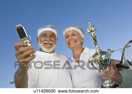 Tennis players holding award cup and photographing View Large Photo Image Stock Image - Tennis players holding award cup and photographing. Fotosearch
