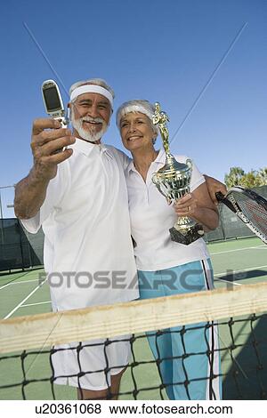 Tennis players holding award cup and photographing View Large Photo Image Stock Photo - Tennis players holding award cup and photographing. Fotosearch
