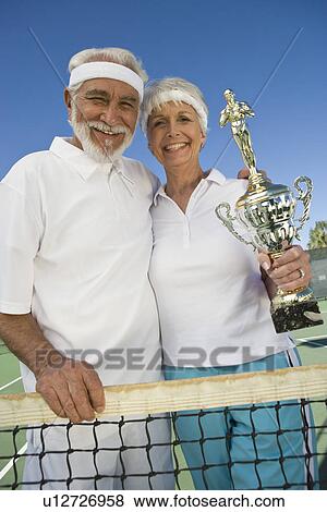 Stock Photo - Tennis players holding award cup. Fotosearch