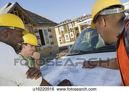 Stock Photograph - Three construction workers studying blueprint. Fotosearch