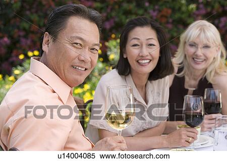 Stock Photography - Three friends drinking wine outdoors, portrait. Fotosearch