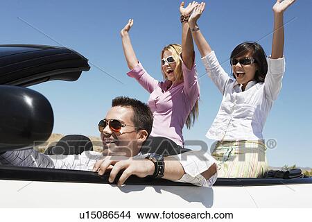 Picture - Three friends driving in convertible car. Fotosearch