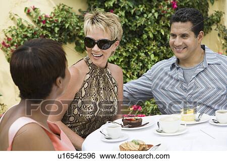 Stock Photograph - Three friends relaxing at outdoor table. Fotosearch