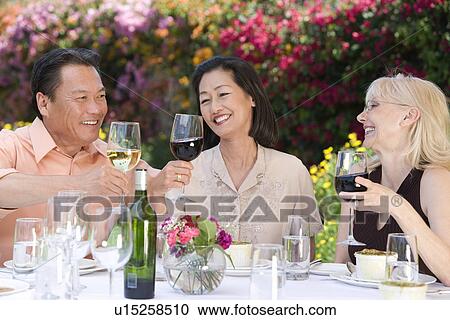 Three friends toasting at outdoor table View Large Photo Image Stock Image - Three friends toasting at outdoor table. Fotosearch