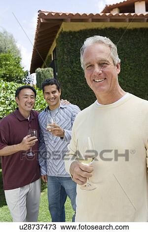 Three male friends drinking wine in garden, portrait View Large Photo Image Stock Image - Three male friends drinking wine in garden, portrait. Fotosearch