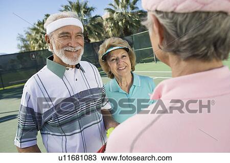 Stock Image - Three people on tennis court. Fotosearch