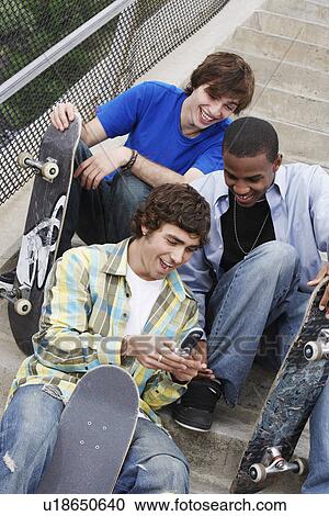 Three skateboarders sitting on stairs using cell phone View Large Photo Image Stock Image - Three skateboarders sitting on stairs using cell phone. Fotosearch