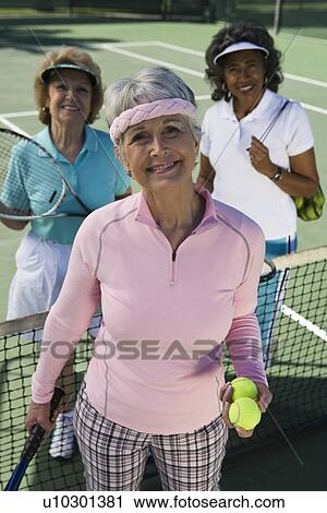 Stock Image - Three women on tennis court, portrait. Fotosearch