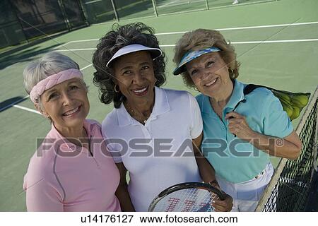 Stock Photo - Three women on tennis court, portrait. Fotosearch