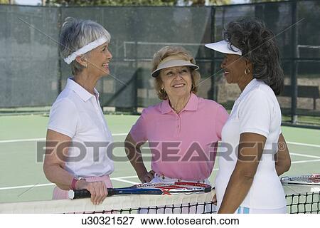 Stock Photo - Three women talking at tennis court. Fotosearch