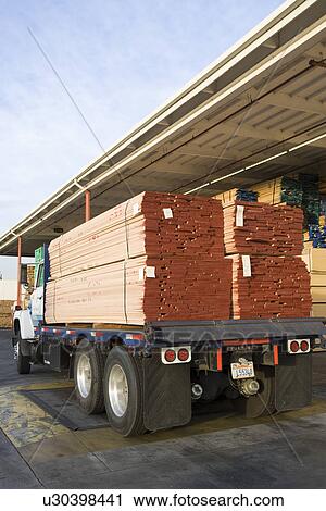 Stock Image - Truck loaded with wood outside warehouse. Fotosearch