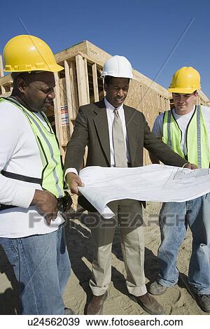 Two construction workers and surveyor studying blueprint View Large Photo Image Stock Photo - Two construction workers and surveyor studying blueprint. Fotosearch
