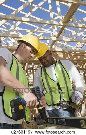 Stock Photo - Two construction workers drilling on site. Fotosearch