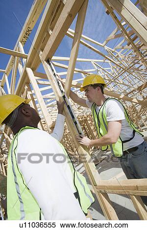 Stock Photography - Two construction workers measuring building framework. Fotosearch