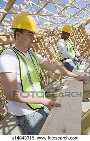 Stock Photography - Two construction workers measuring wooden plank. Fotosearch