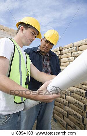 Stock Image - Two construction workers studying blueprints. Fotosearch