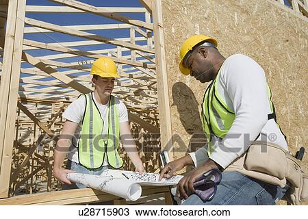 Two construction workers studying blueprints View Large Photo Image Stock Image - Two construction workers studying blueprints. Fotosearch