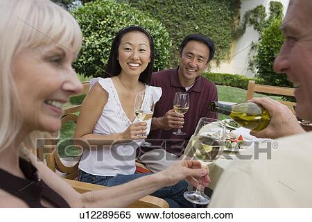 Stock Photography - Two couples drinking wine in garden. Fotosearch