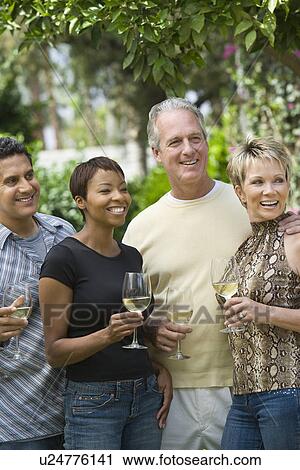 Stock Image - Two couples drinking wine outdoors. Fotosearch
