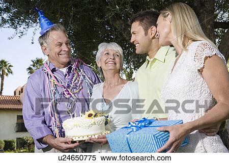 Stock Photography - Two couples on birthday party in garden, smiling. Fotosearch