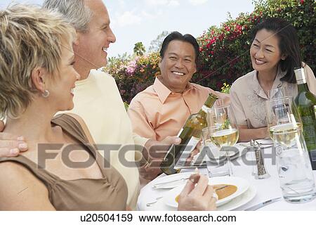 Two elegant couples dining at table outdoors View Large Photo Image Stock Photo - Two elegant couples dining at table outdoors. Fotosearch