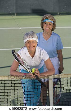 Stock Image - Two female tennis players on court. Fotosearch