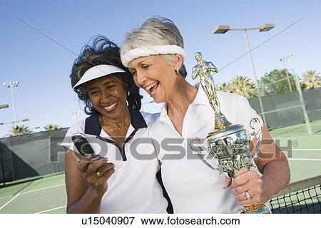 Stock Photo - Two female tennis players with award cup. Fotosearch