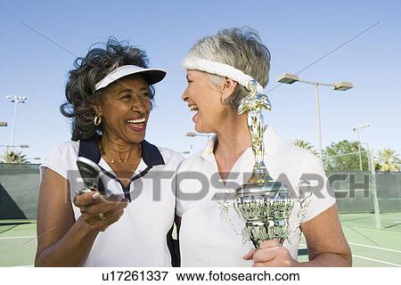 Stock Photo - Two female tennis players with award cup. Fotosearch