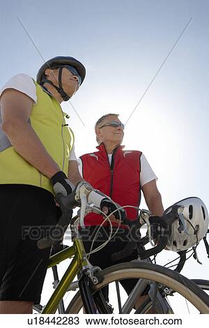 Stock Image - Two men on bicycle ride, portrait, low angle view. Fotosearch
