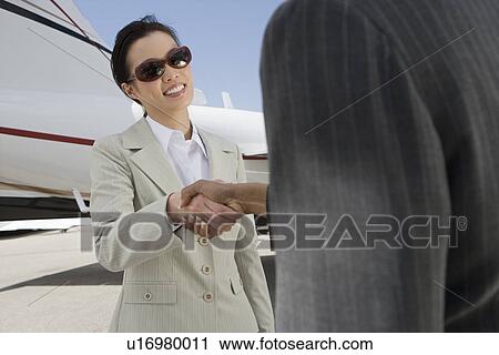 Two mid-adult businesswomen shaking hands in front of private plane. View Large Photo Image Stock Image - Two mid-adult businesswomen shaking hands in front of private plane.. Fotosearch