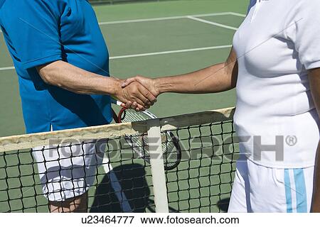Stock Photo - Two people shaking hands over tennis net. Fotosearch