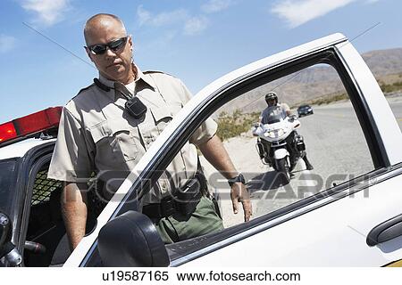 Stock Photography - Two police officers stopping on side of desert road. Fotosearch