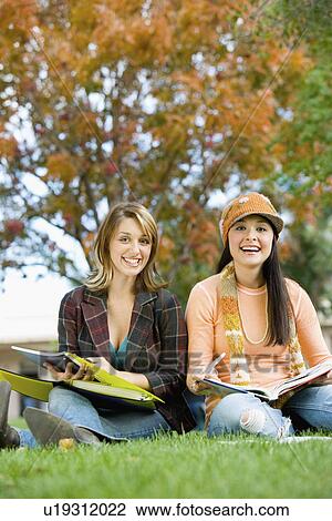 Two students studying outdoors, (portrait) View Large Photo Image Stock Image - Two students studying outdoors, (portrait). Fotosearch