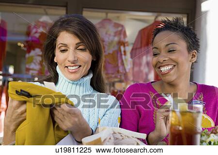 Stock Photography - Two women at cafe, looking at clothes. Fotosearch