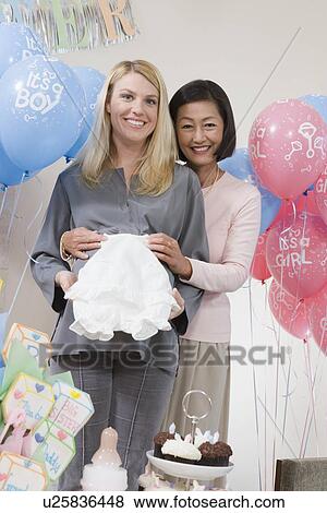 Stock Photo - Two Women holding a gift at a Baby Shower. Fotosearch