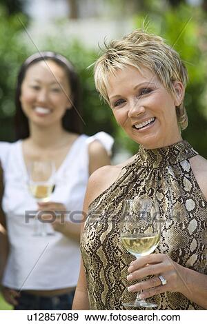 Two women holding wine outdoors, portrait View Large Photo Image Stock Photo - Two women holding wine outdoors, portrait. Fotosearch