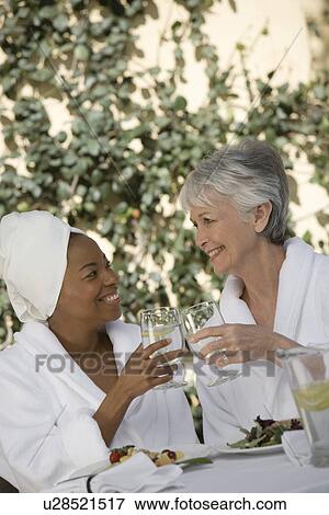 Two women in bathrobes, toasting drinks View Large Photo Image Stock Photo - Two women in bathrobes, toasting drinks. Fotosearch