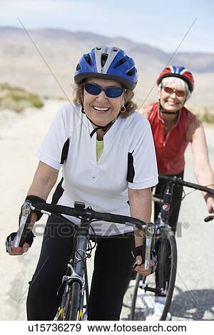 Stock Photo - Two women on bicycle ride, portrait. Fotosearch