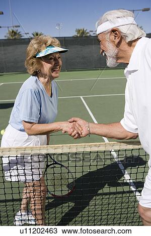 Two women shaking hands over tennis net View Large Photo Image Stock Image - Two women shaking hands over tennis net. Fotosearch