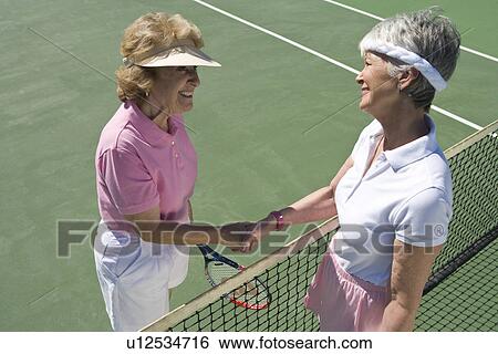 Two women shaking hands over tennis net View Large Photo Image Stock Photograph - Two women shaking hands over tennis net. Fotosearch