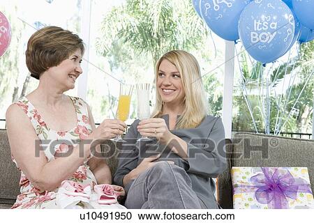 Stock Image - Two Women toasting drinks at a Baby Shower. Fotosearch