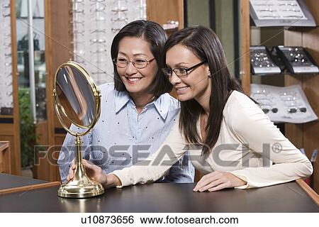 Two women trying on eyeglasses in store View Large Photo Image Stock Photograph - Two women trying on eyeglasses in store. Fotosearch