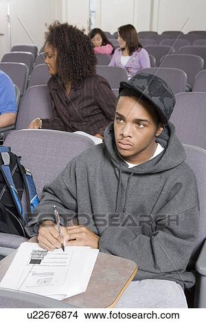 Picture - University student writing in lecture hall. Fotosearch
