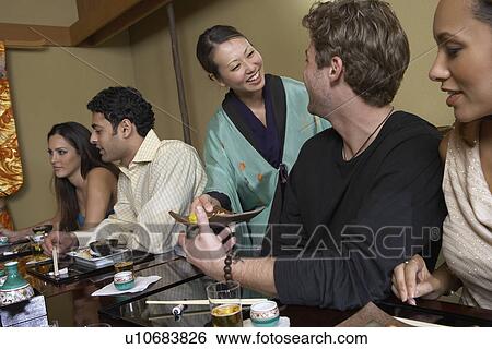 Stock Photograph - Waitress serving sushi to restaurant. Fotosearch